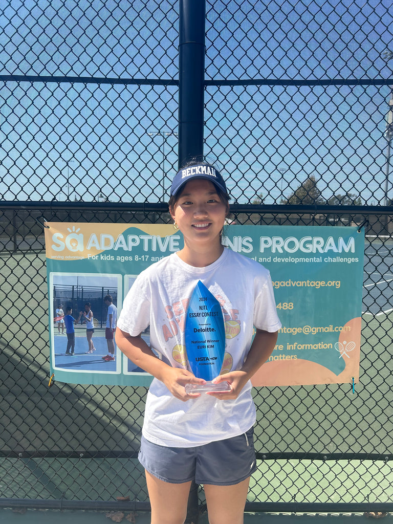 Serving Advantage Coach and USTA Foundation Winner, Euri Kim, standing in front of the Serving Advantage banner, outside the tennis court, holding her trophy 